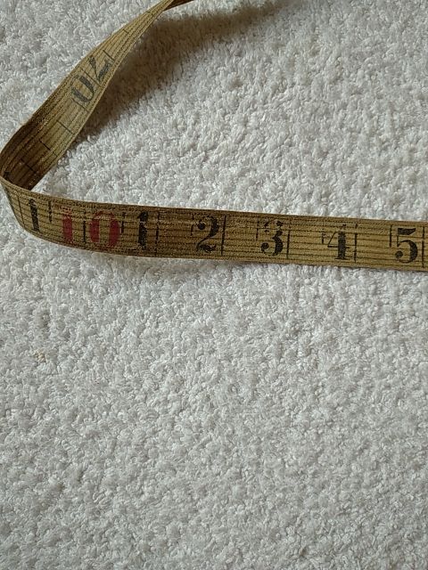 ANTIGUA CINTA MÉTRICA DE TELA, CUERO Y BRONCE.