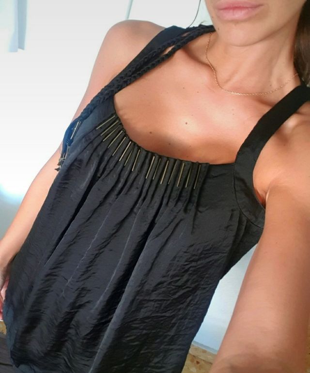 Blusa negra larga con detalles metálicos, raso.