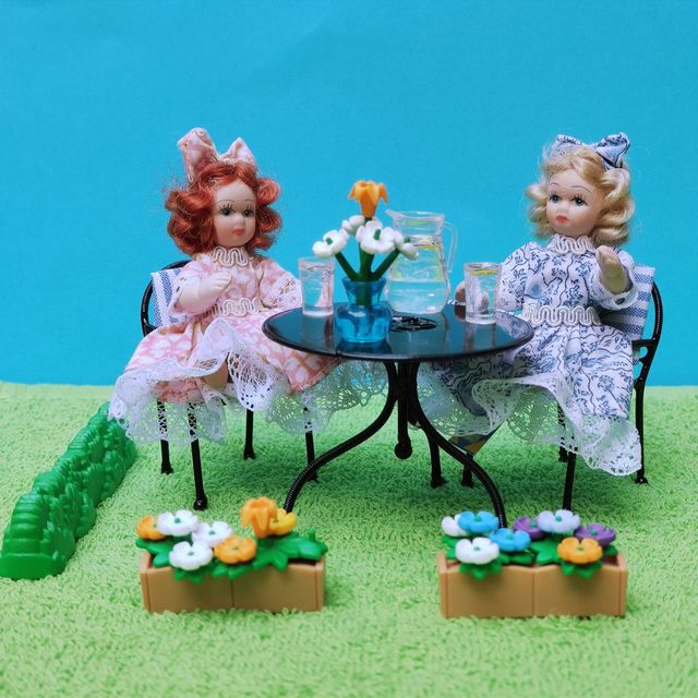 Escena muñecas porcelana en el jardín miniatura