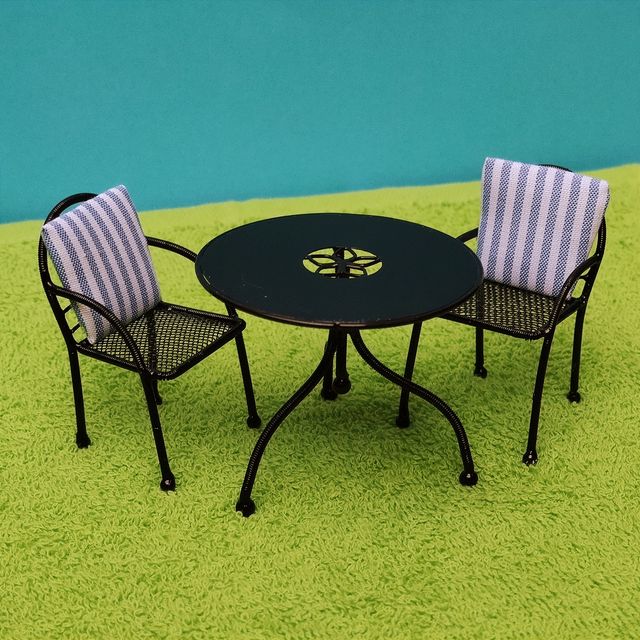 Escena muñecas porcelana en el jardín miniatura