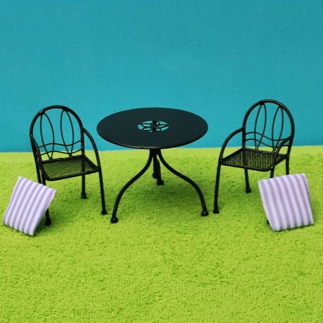 Escena muñecas porcelana en el jardín miniatura