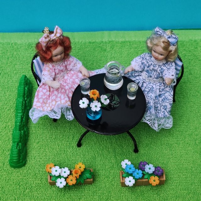 Escena muñecas porcelana en el jardín miniatura