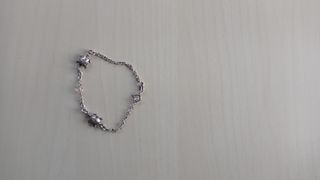 Pulsera plata con tortugas y piedra rosa.