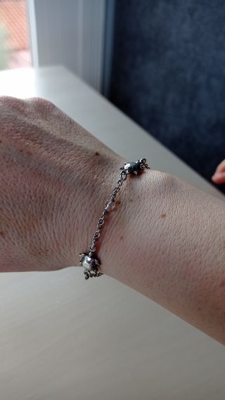 Pulsera plata con tortugas y piedra rosa.