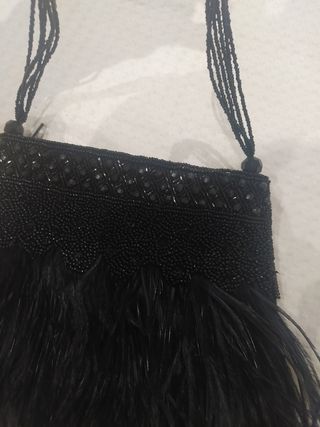 Bolsito negro con plumas y piedritas.