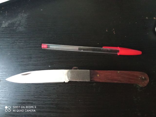 cuchillo plegable negro con mando de madera, como