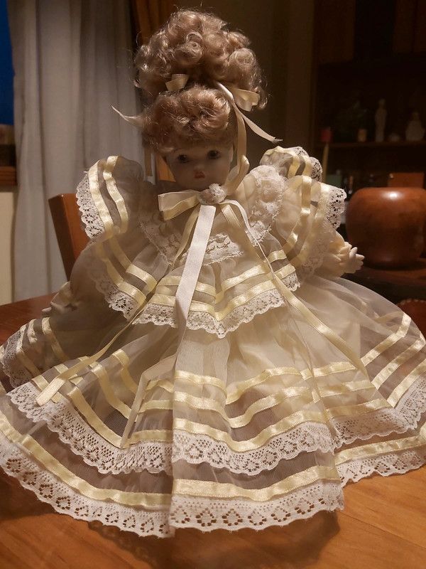 Boneca porcelana antiga com vestido em tom amarelo