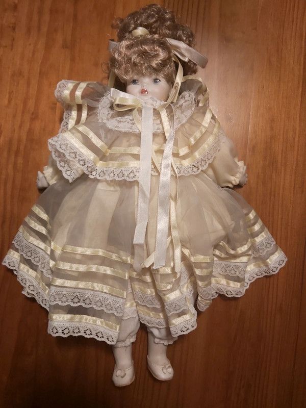 Boneca porcelana antiga com vestido em tom amarelo