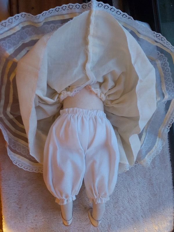 Boneca porcelana antiga com vestido em tom amarelo