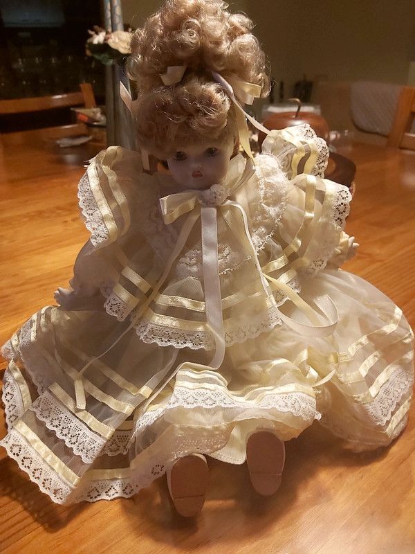 Boneca porcelana antiga com vestido em tom amarelo