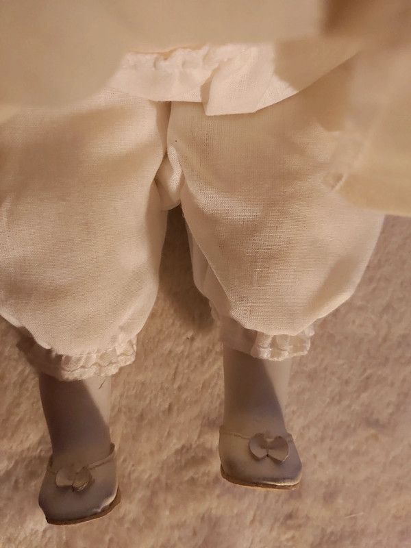 Boneca porcelana antiga com vestido em tom amarelo