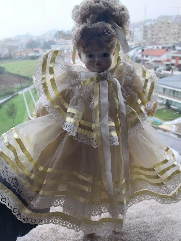 Boneca porcelana antiga com vestido em tom amarelo