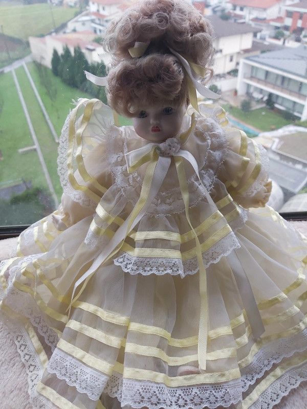 Boneca porcelana antiga com vestido em tom amarelo