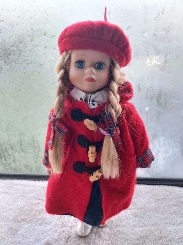 Boneca de porcelana com boina e casaco vermelho