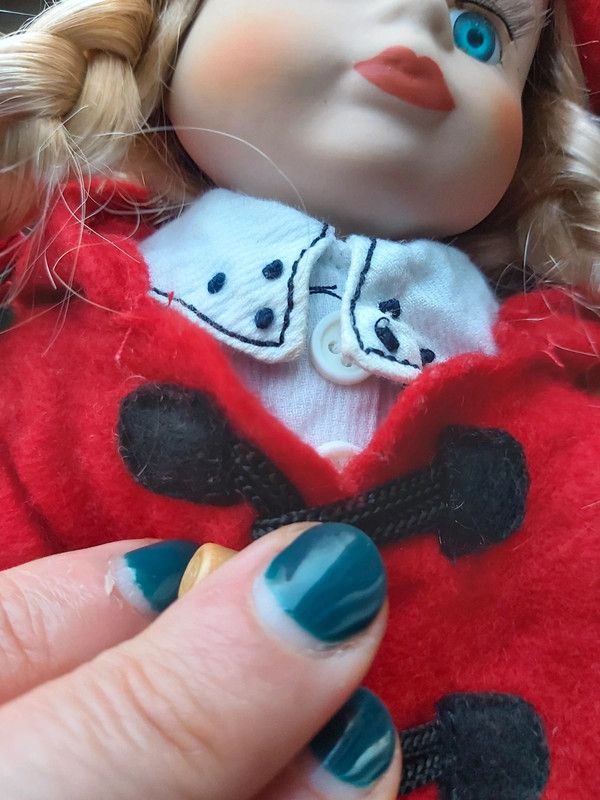 Boneca de porcelana com boina e casaco vermelho