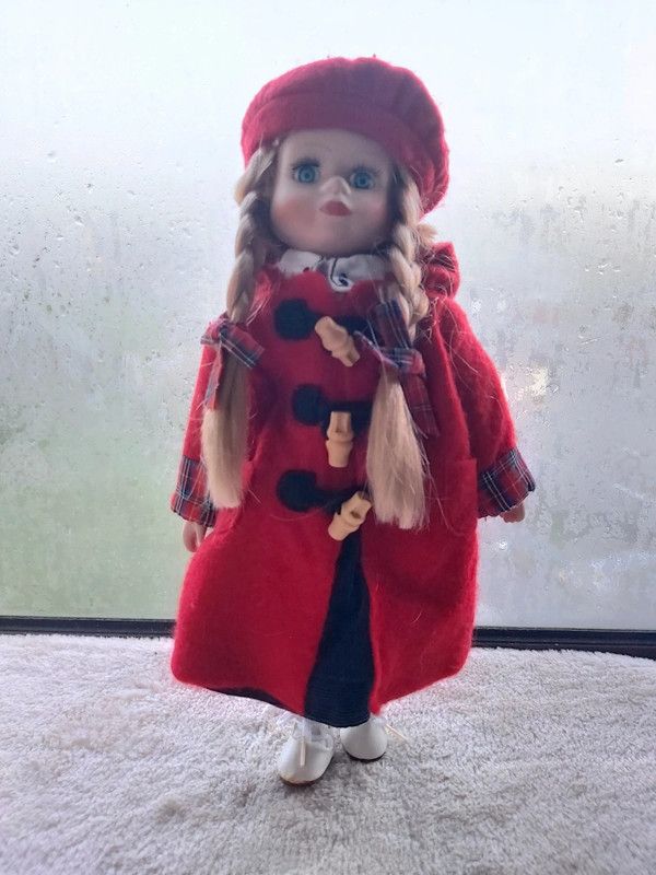 Boneca de porcelana com boina e casaco vermelho