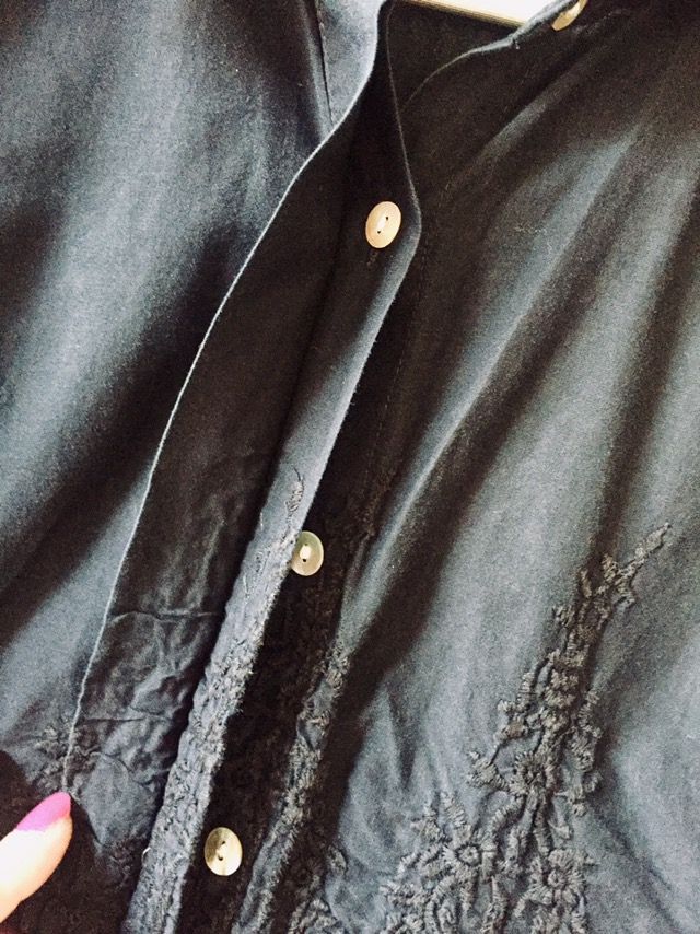 Camisa negra bordada, con botonadura invisible.