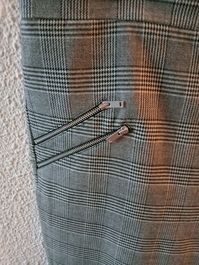 Pantalón pata de gallo con varias cremalleras.