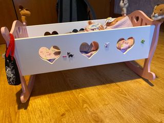 Cuna de juguete con muñeca y acesorios.