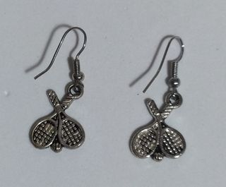 Pendientes plateados, raquetas de tenis y pelota