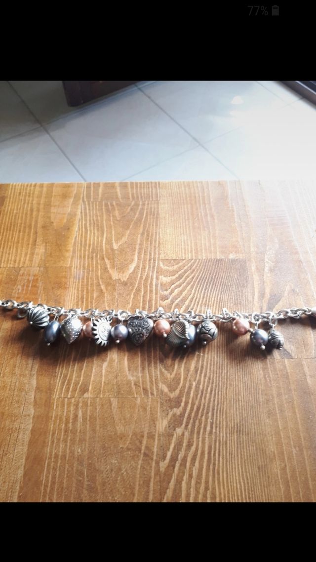 Bracciale color argento con ciondoli. Nuovo