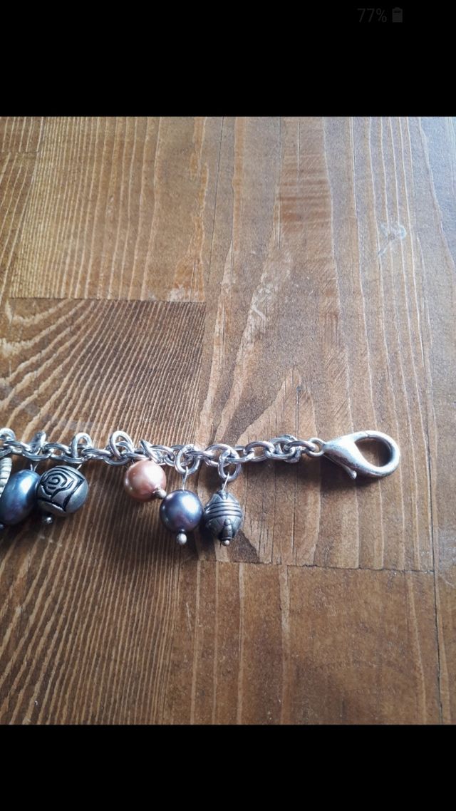 Bracciale color argento con ciondoli. Nuovo
