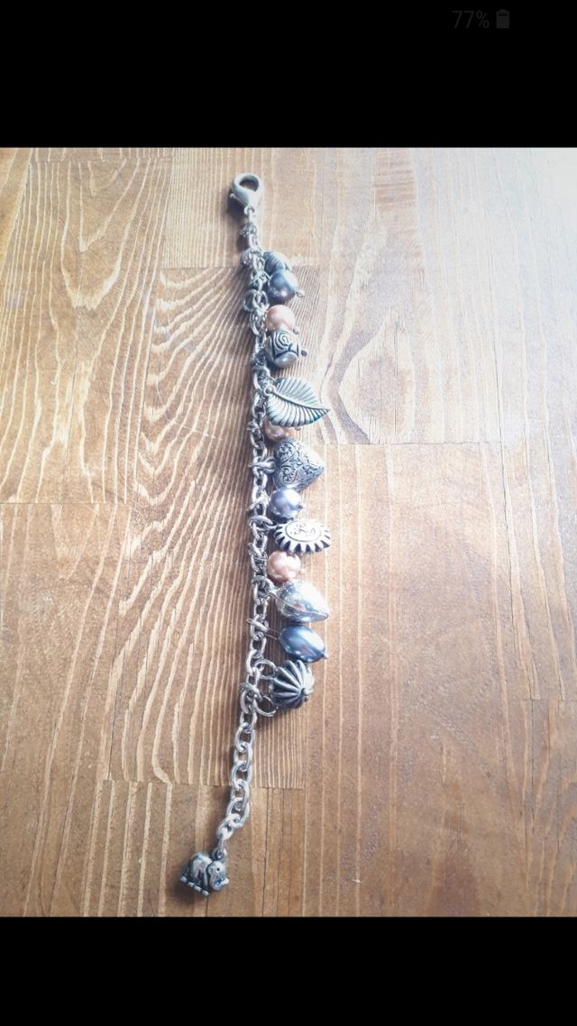 Bracciale color argento con ciondoli. Nuovo