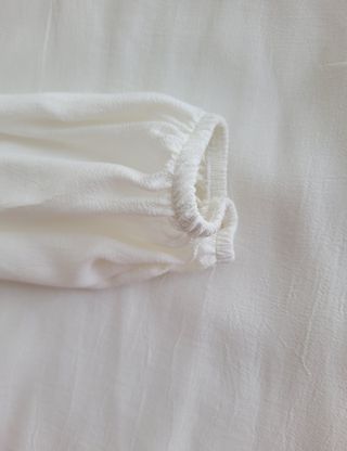 BLUSA MANGA LARGA CON ADORNOS.