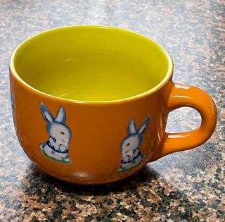 Tazza in ceramica, arancione e gialla, usata 