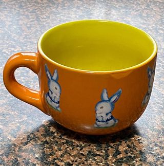 Tazza in ceramica, arancione e gialla, usata 