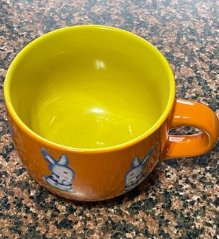 Tazza in ceramica, arancione e gialla, usata 