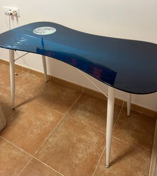 Mesa con superficie de vidrio, patas metálicas.