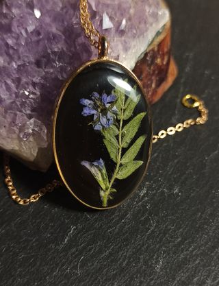 Colgante ovalo dorado de resina con flor morada