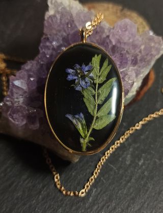 Colgante ovalo dorado de resina con flor morada