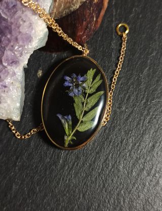 Colgante ovalo dorado de resina con flor morada