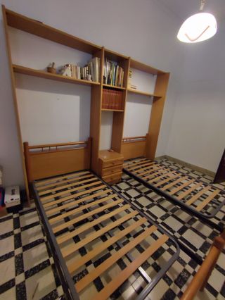 Dos camas sin colchón, mueble y mesilla