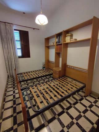 Dos camas sin colchón, mueble y mesilla