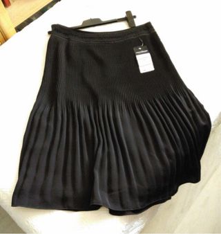 Elegante falda negra plisada, con pasamanería