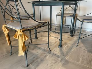 Mesa de cristal con 4 sillas y cojines.