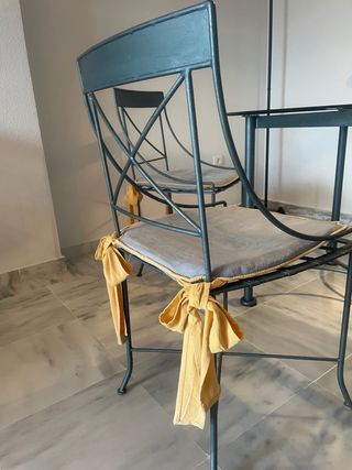 Mesa de cristal con 4 sillas y cojines.