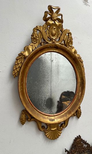 Elegante espejo ovalado dorado en oro fino.