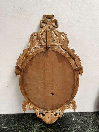 Elegante espejo ovalado dorado en oro fino.
