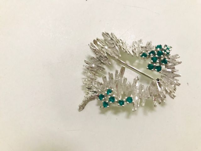 Broche plateado con piedras verdes
