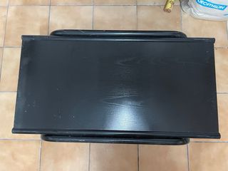 Mesa auxiliar negra con revistero metálico.