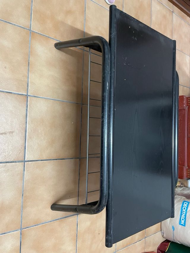 Mesa auxiliar negra con revistero metálico.