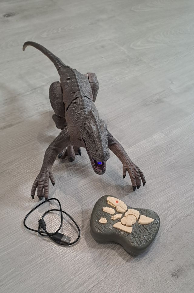 Dinosaurio con mando + libro + figuras