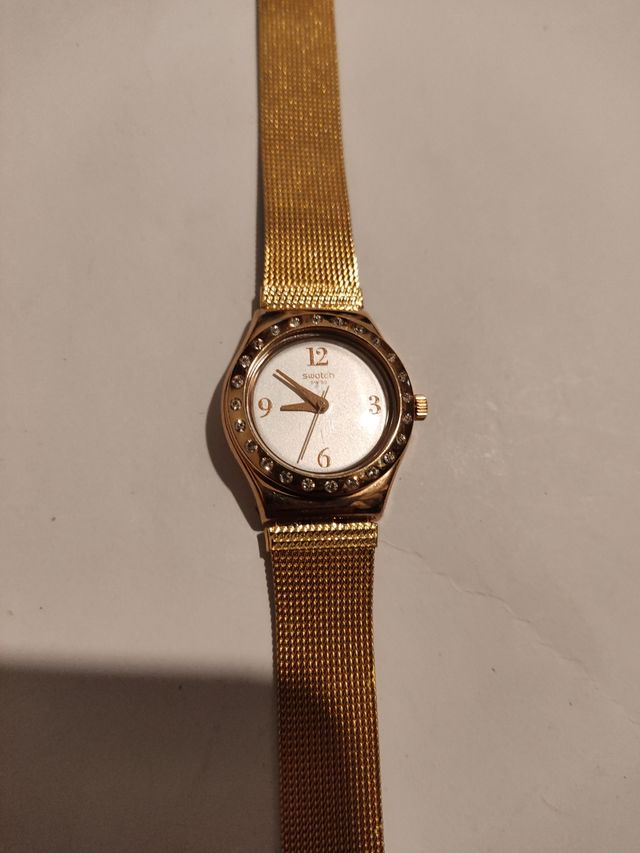 Reloj marca Swatch terminado en oro.