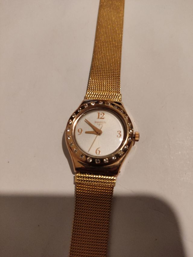 Reloj marca Swatch terminado en oro.