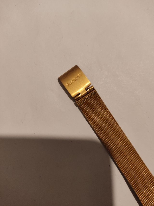 Reloj marca Swatch terminado en oro.