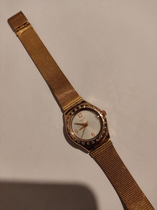 Reloj marca Swatch terminado en oro.